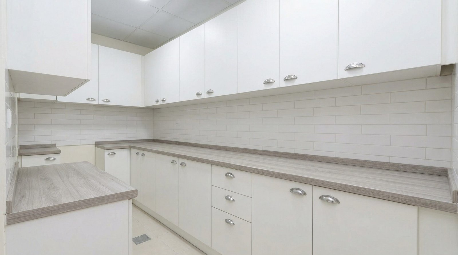 Clean white melamine kitchen cabinets with chrome handles representing fair value installation in UAE apartment