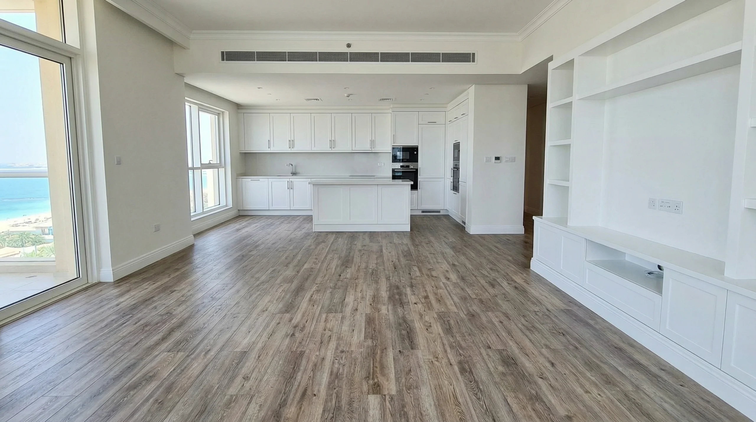 Weathered oak waterproof laminate flooring in a modern JBR apartment living and kitchen area near custom joinery.