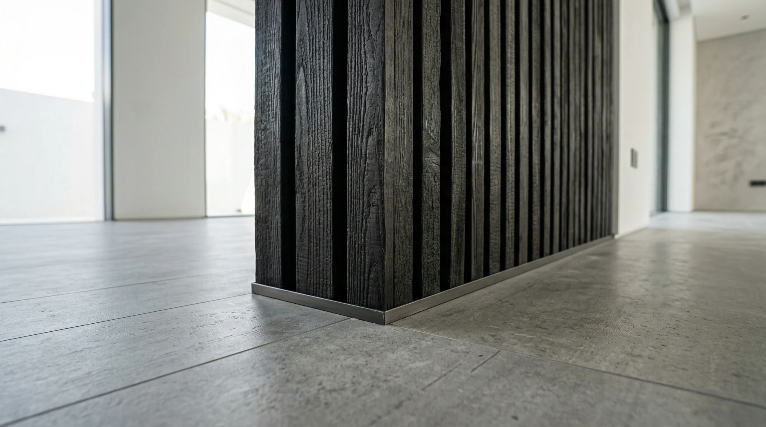 Grey concrete effect SPC flooring adjacent to charred wood slat partition.