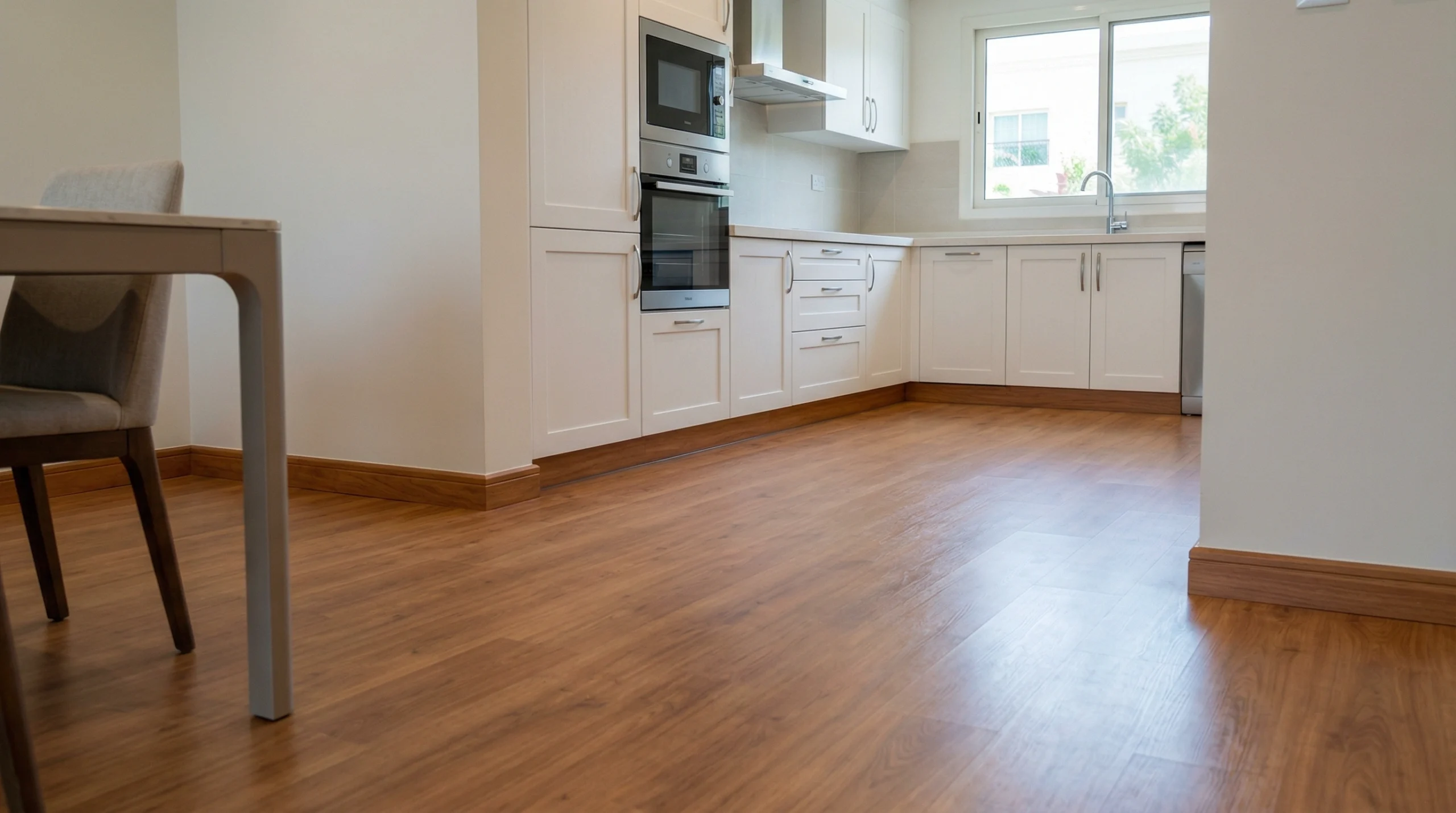 Warm maple laminate flooring with integrated wooden baseboards in Mirdif.