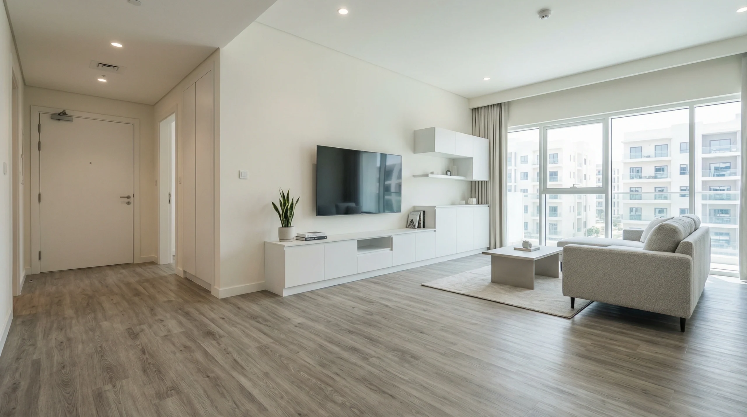 Practical greige wood laminate flooring in a modern Silicon Oasis apartment near sleek white joinery.