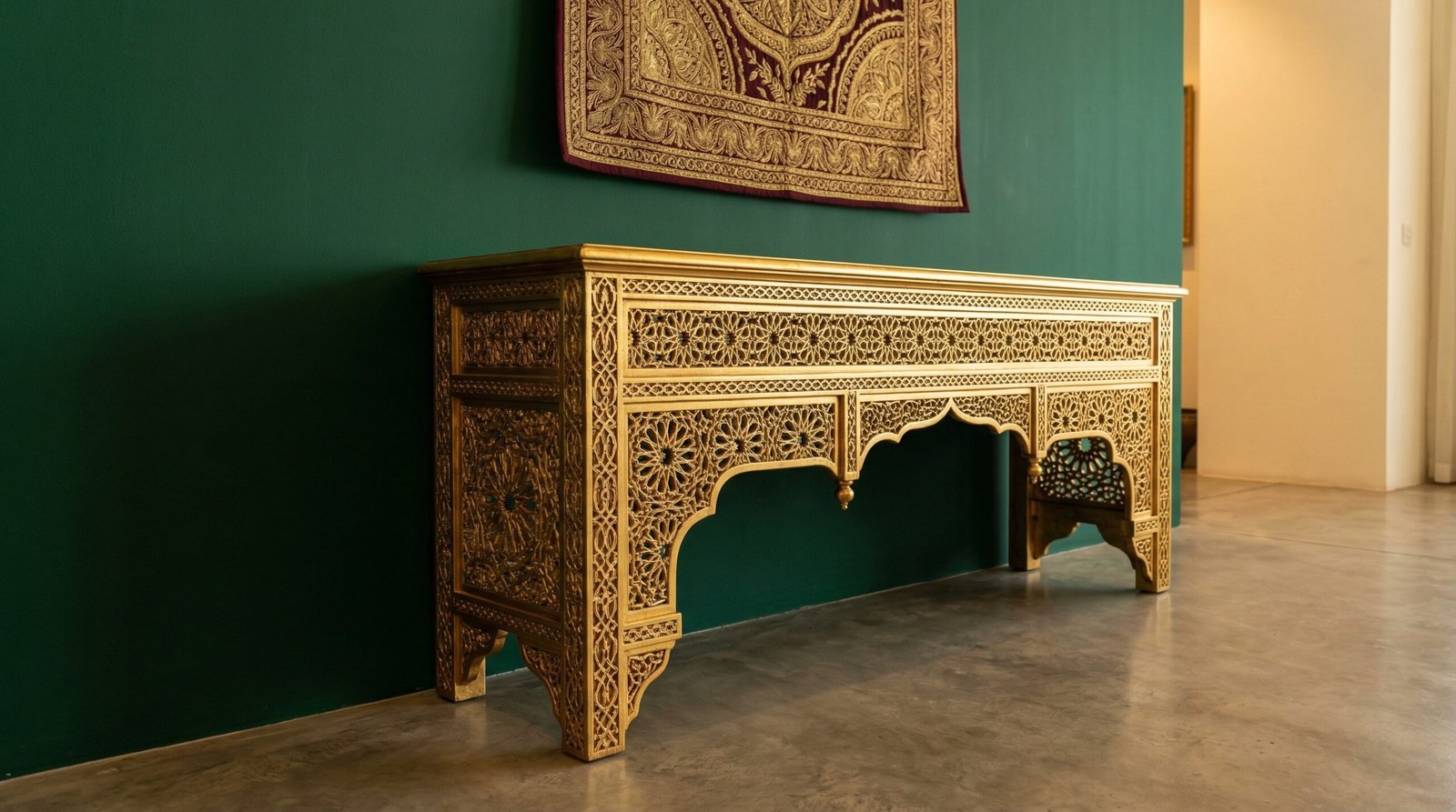 Ornate hand-carved gold leaf console table in a traditional UAE majlis setting.