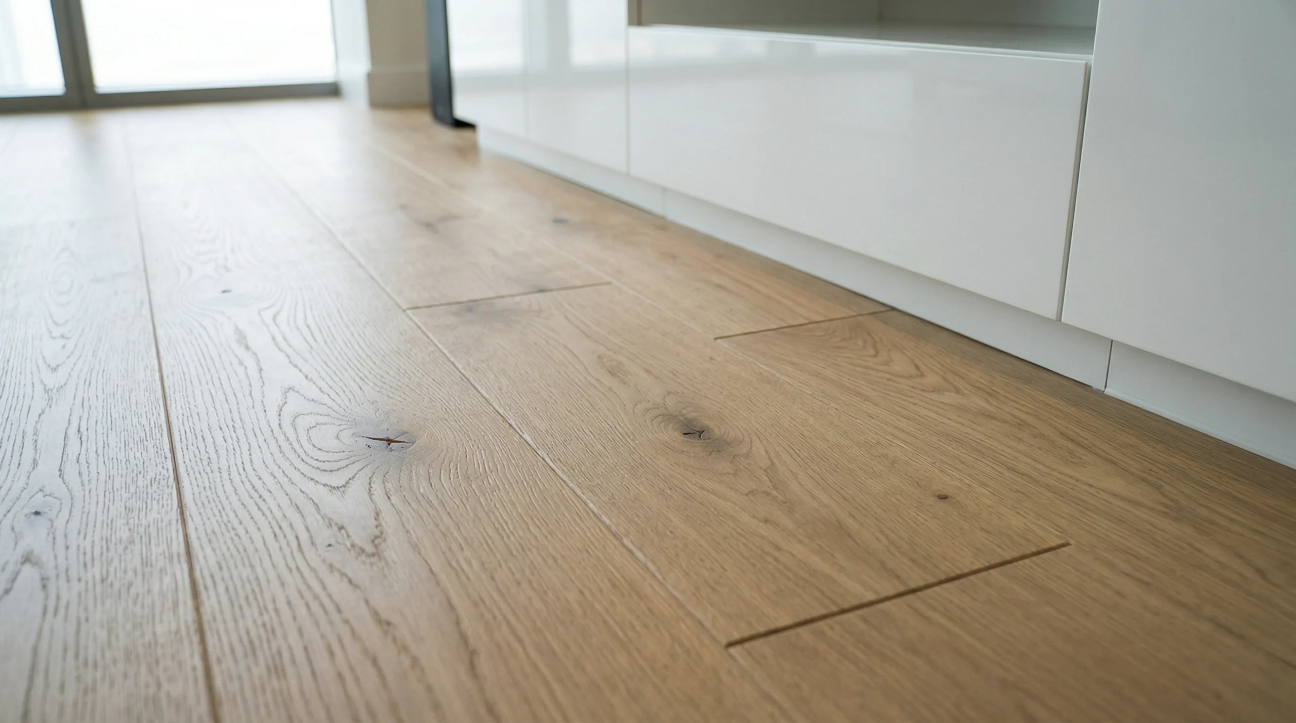 Close-up of authentic registered embossed texture on premium oak laminate flooring near custom white joinery.