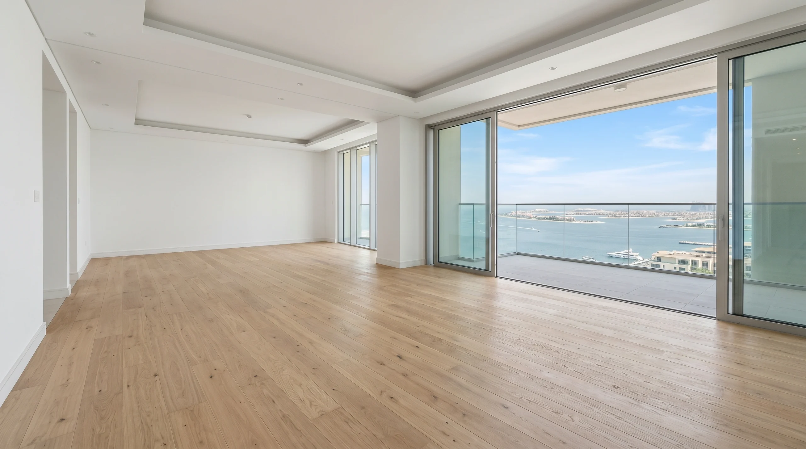 Light linen-toned engineered oak hardwood flooring installed in Palm Jumeirah waterfront apartment with sea view balcony and coastal natural light