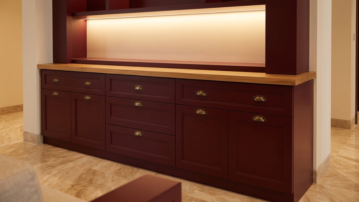 Custom built-in entryway storage cabinet in burgundy lacquer with brass handles and oak top in MBR City Dubai villa